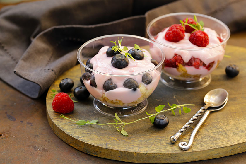 Две стъклени купички с плодов йогурт, декорирани с горски плодове