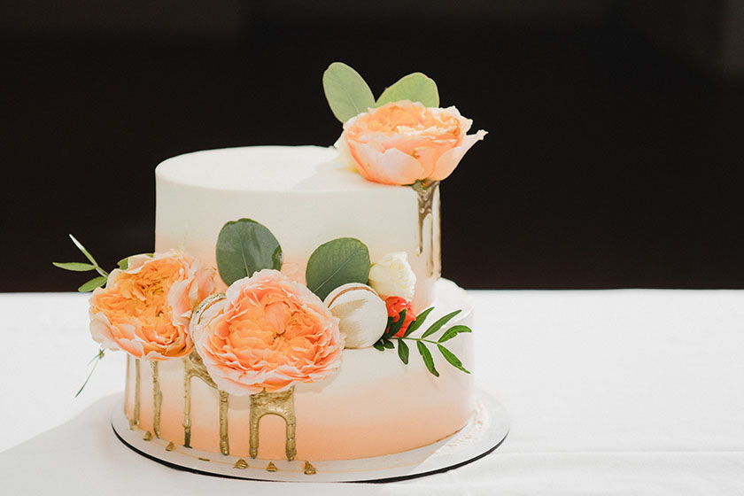 Стилна двуетажна сватбена торта с декорация от цветя и френски макарони